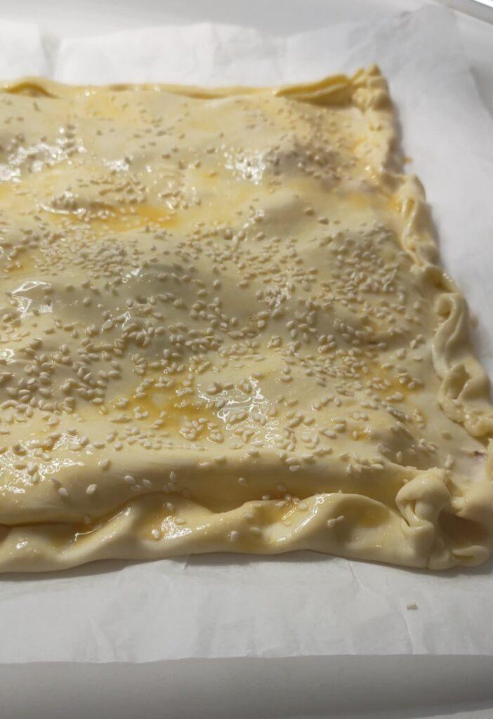 cospargere la torta salata di pasta sfoglia con semi di sesamo prima della cottura