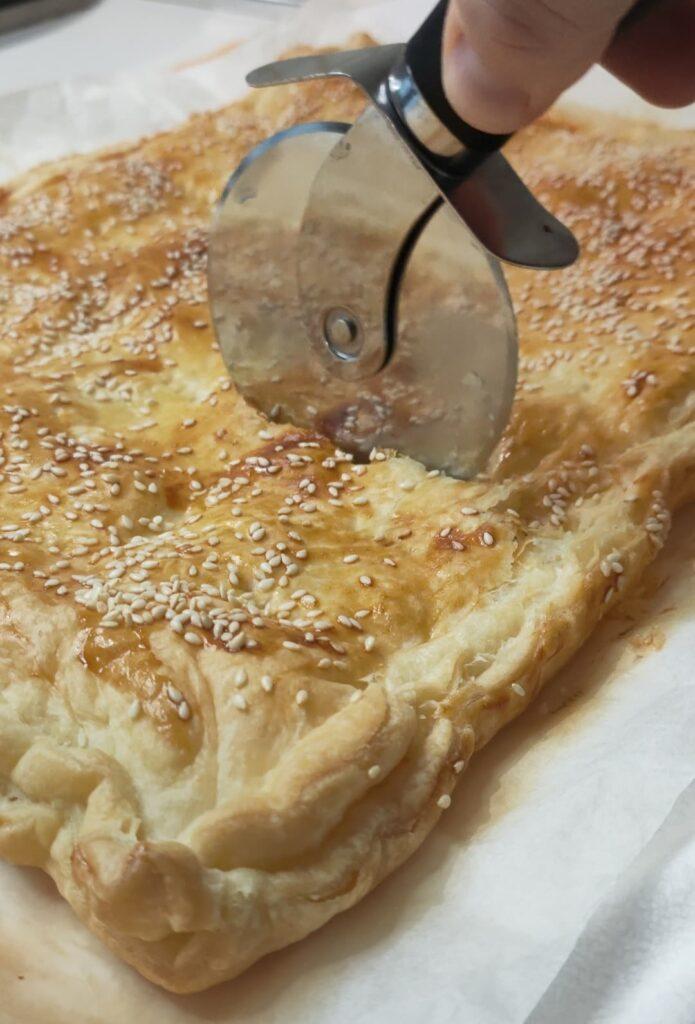 torta salata di pasta sfoglia con prosciutto e mozzarella la superficie dorata con semi di sesamo