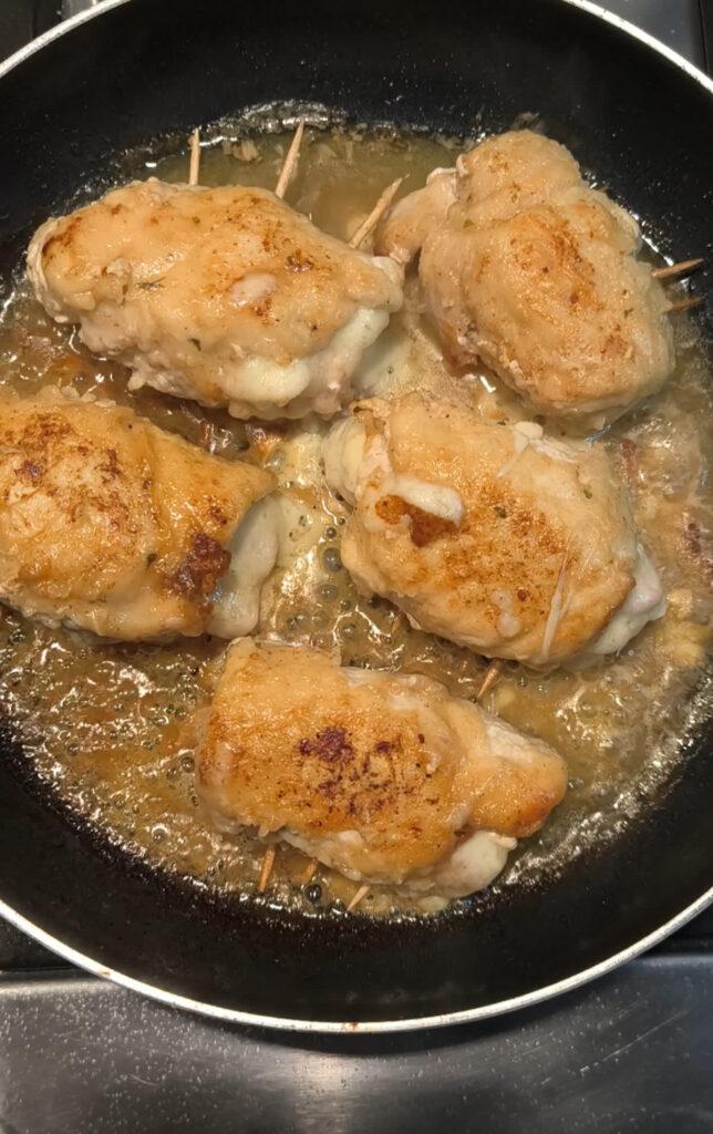 Involtini di pollo con prosciutto e scamorza durante la cottura in padella