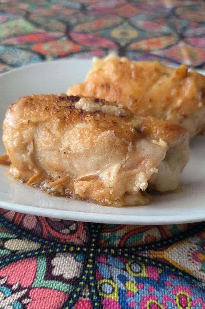 Involtini di pollo con prosciutto e scamorza serviti caldi nel piatto